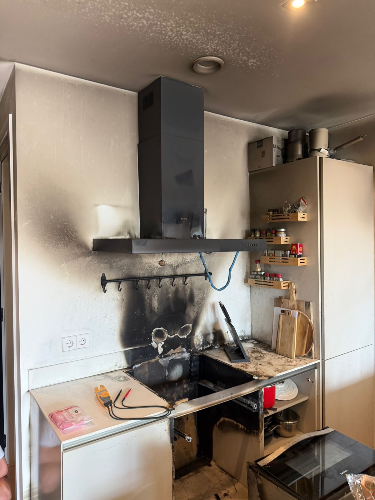 Keuken met brandschade: roet op de wand en het plafond rond het kookgedeelte en de afzuigkap