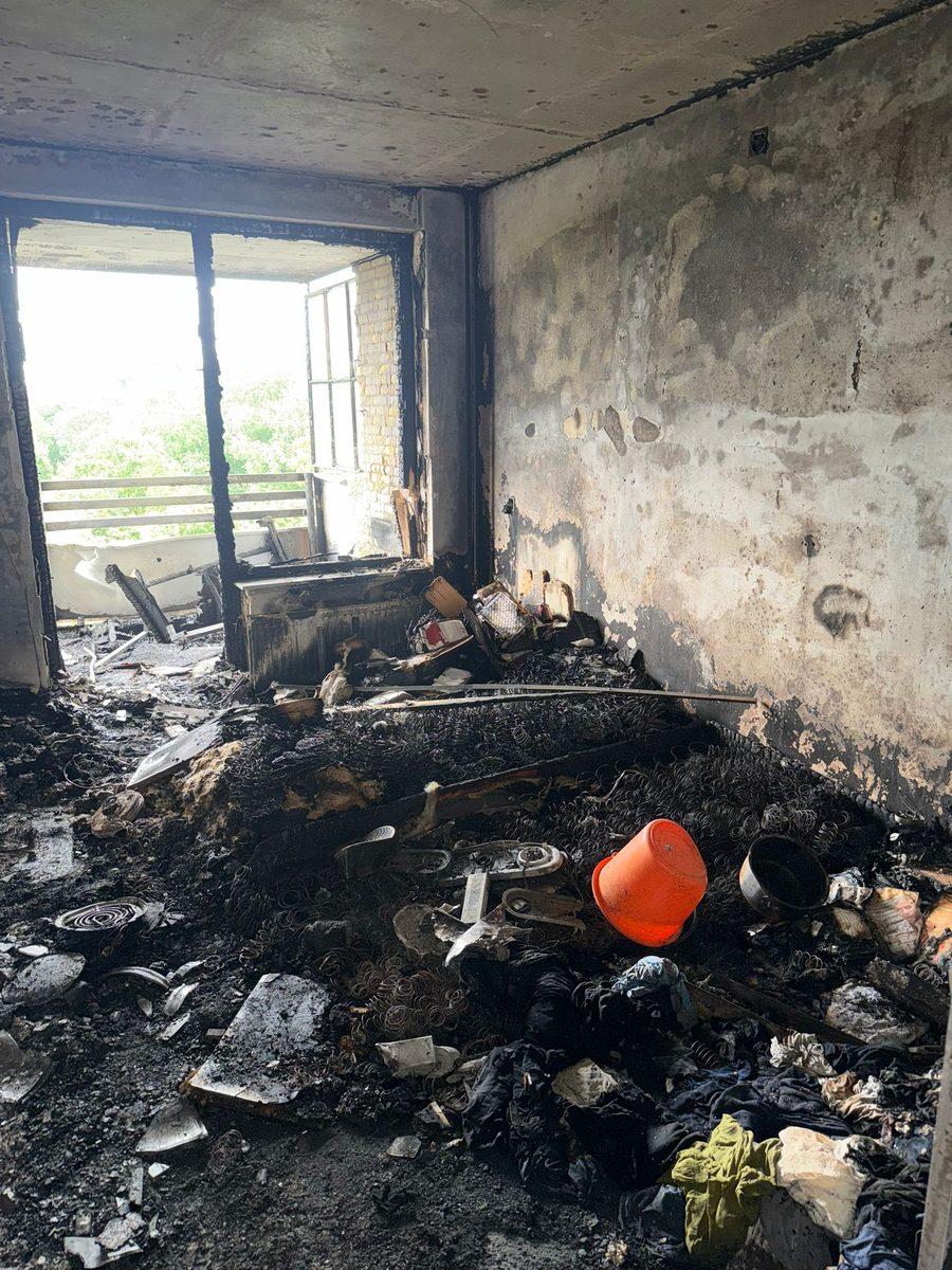 Volledig uitgebrande kamer: verkoolde muren en plafond, de resten van een bed en verbrande spullen op de vloer